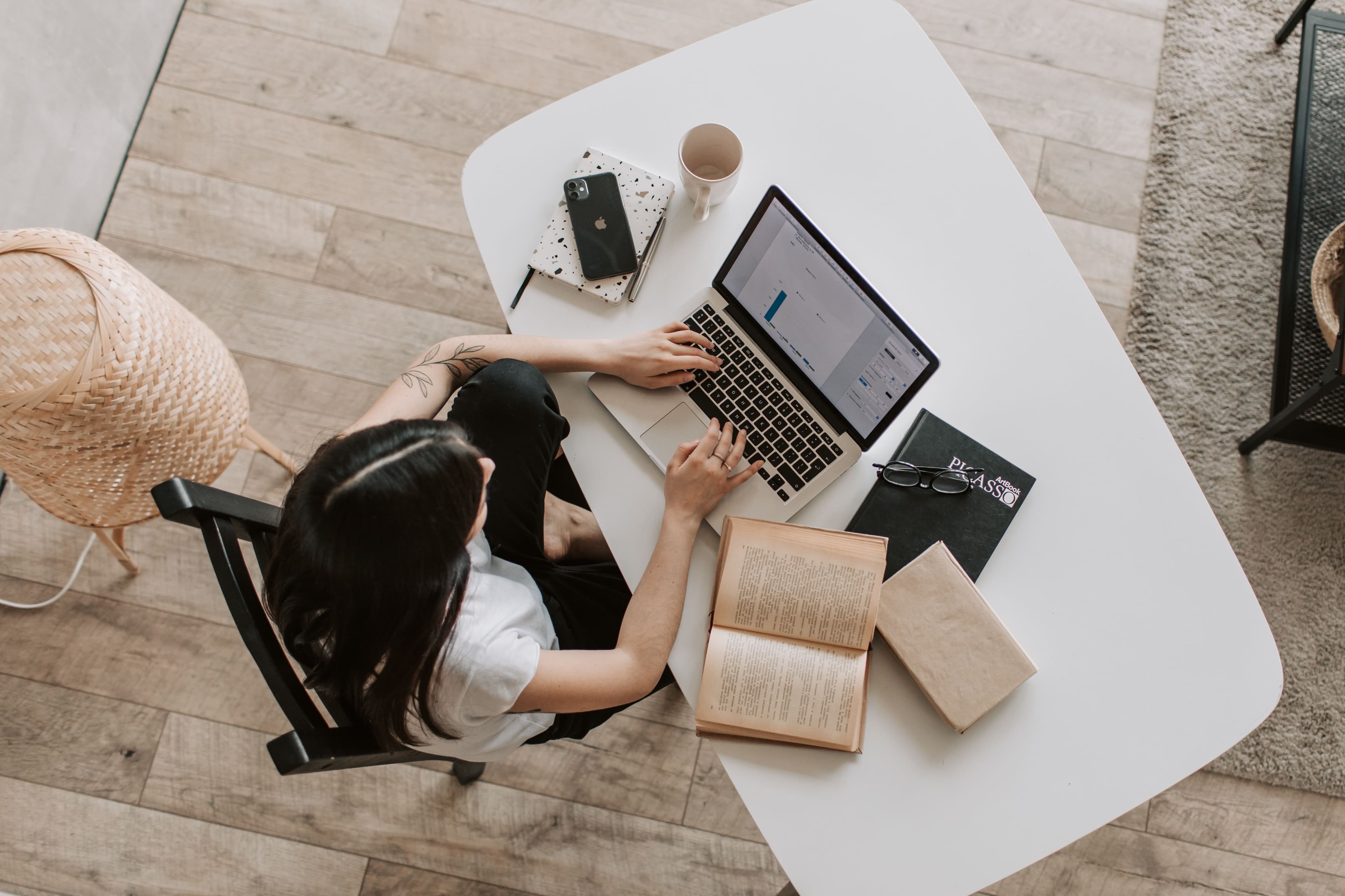 Person working late on a laptop at a wooden desk with notes and coffee. Photo: Andrea Piacquadio, Pexels